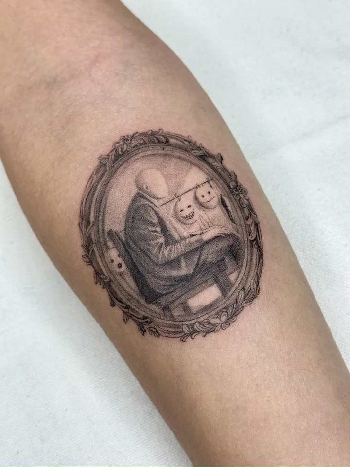 Fine-line tattoo by nurse.tattoo: a framed portrait with two masks, on a forearm