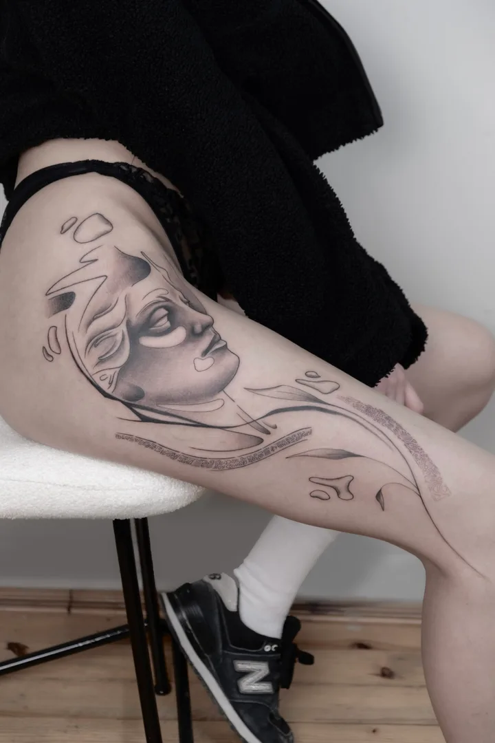 A sleeping face in profile among broken shapes and stipple, black and grey along the thigh